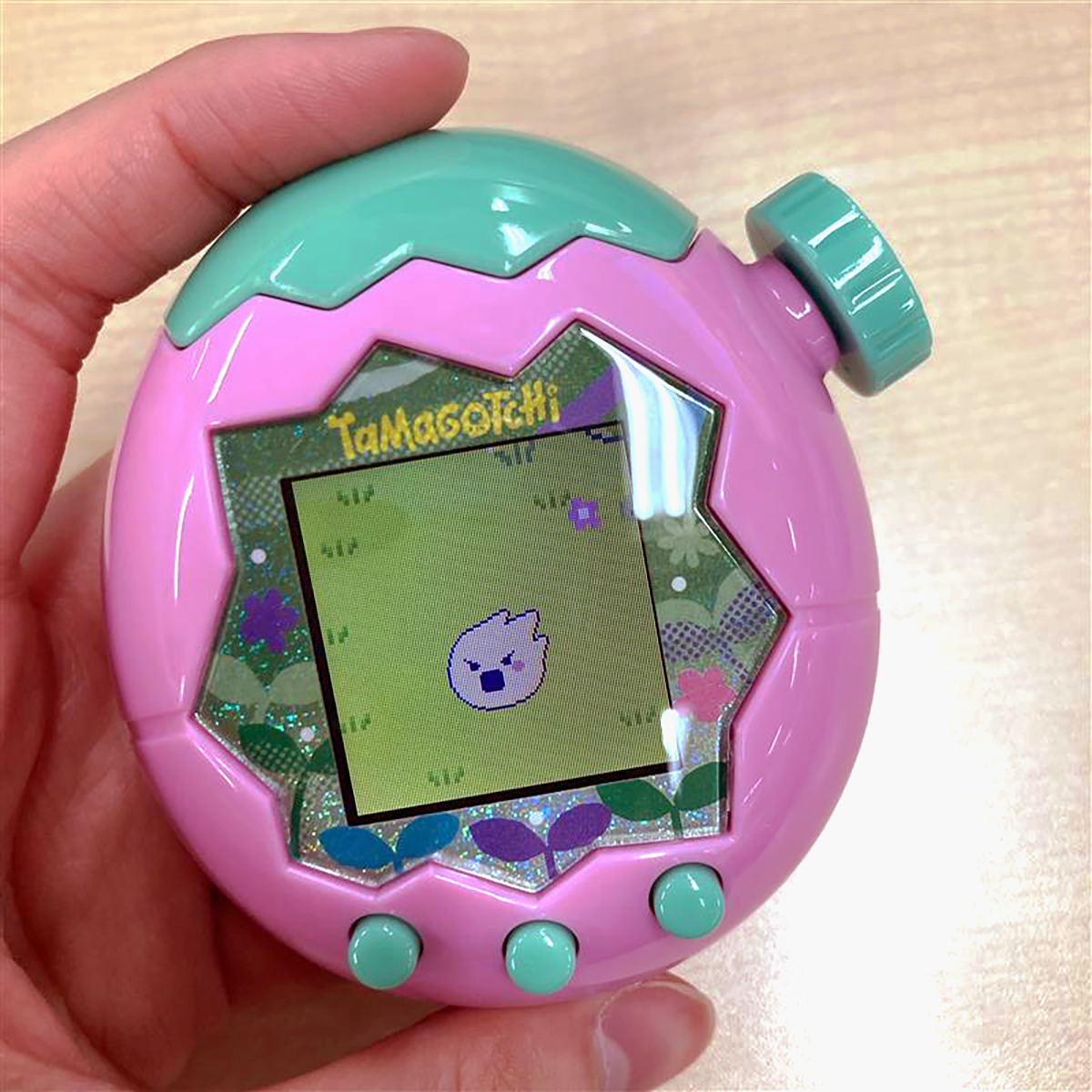 Schermo del paradiso che mostra un Tamagotchi rotondo e giallo che viene sollevato